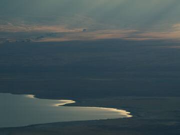 a landscape with a lake and sun rays
