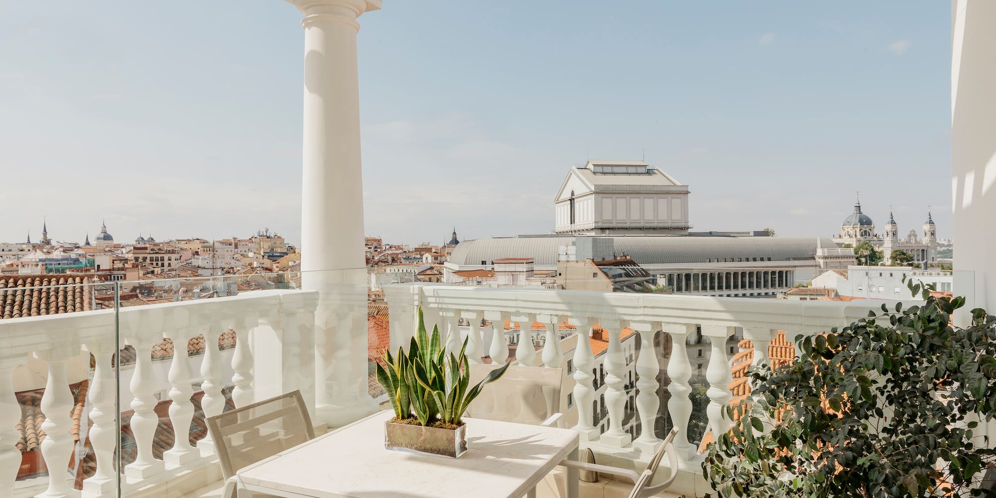 a table and chairs on a balcony with a city in the background