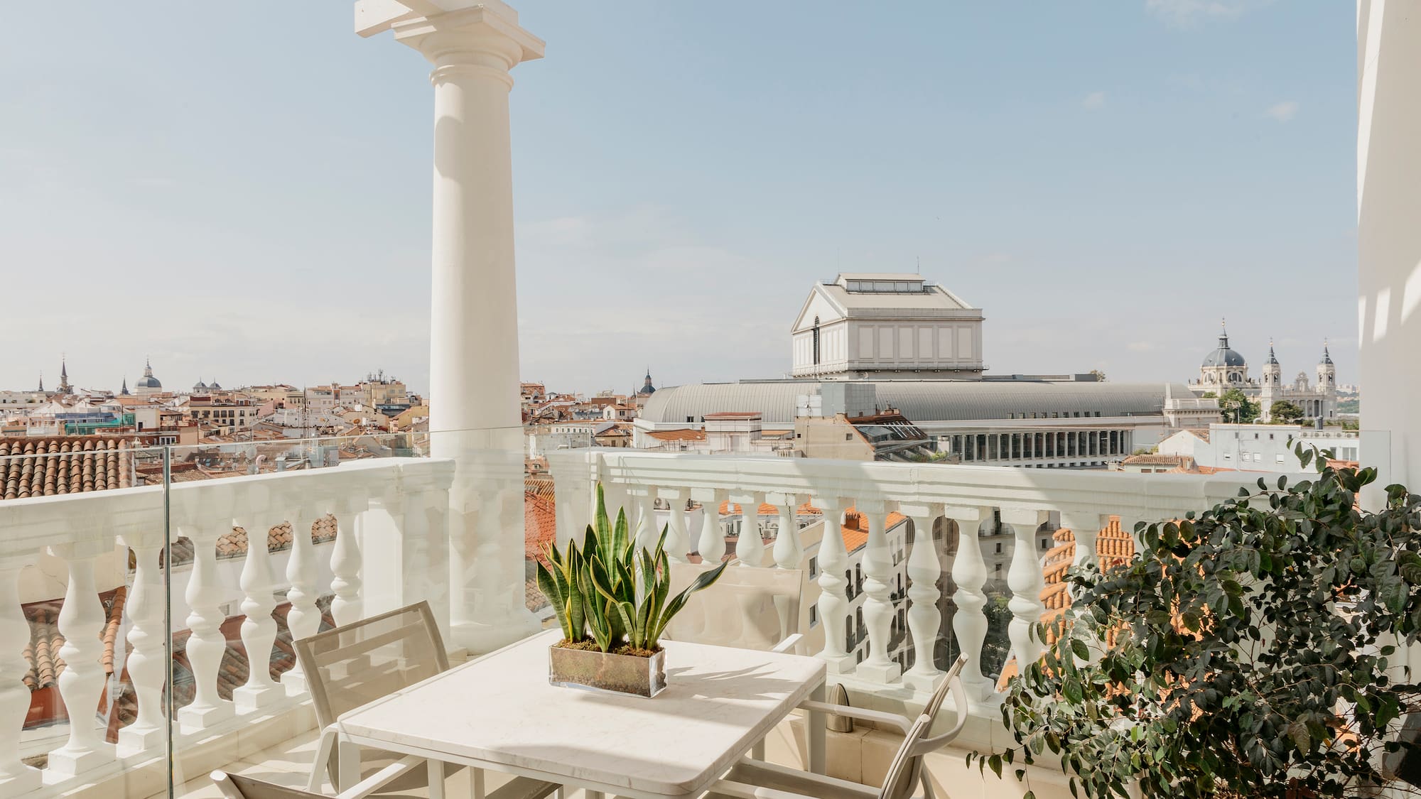 a table and chairs on a balcony with a city in the background