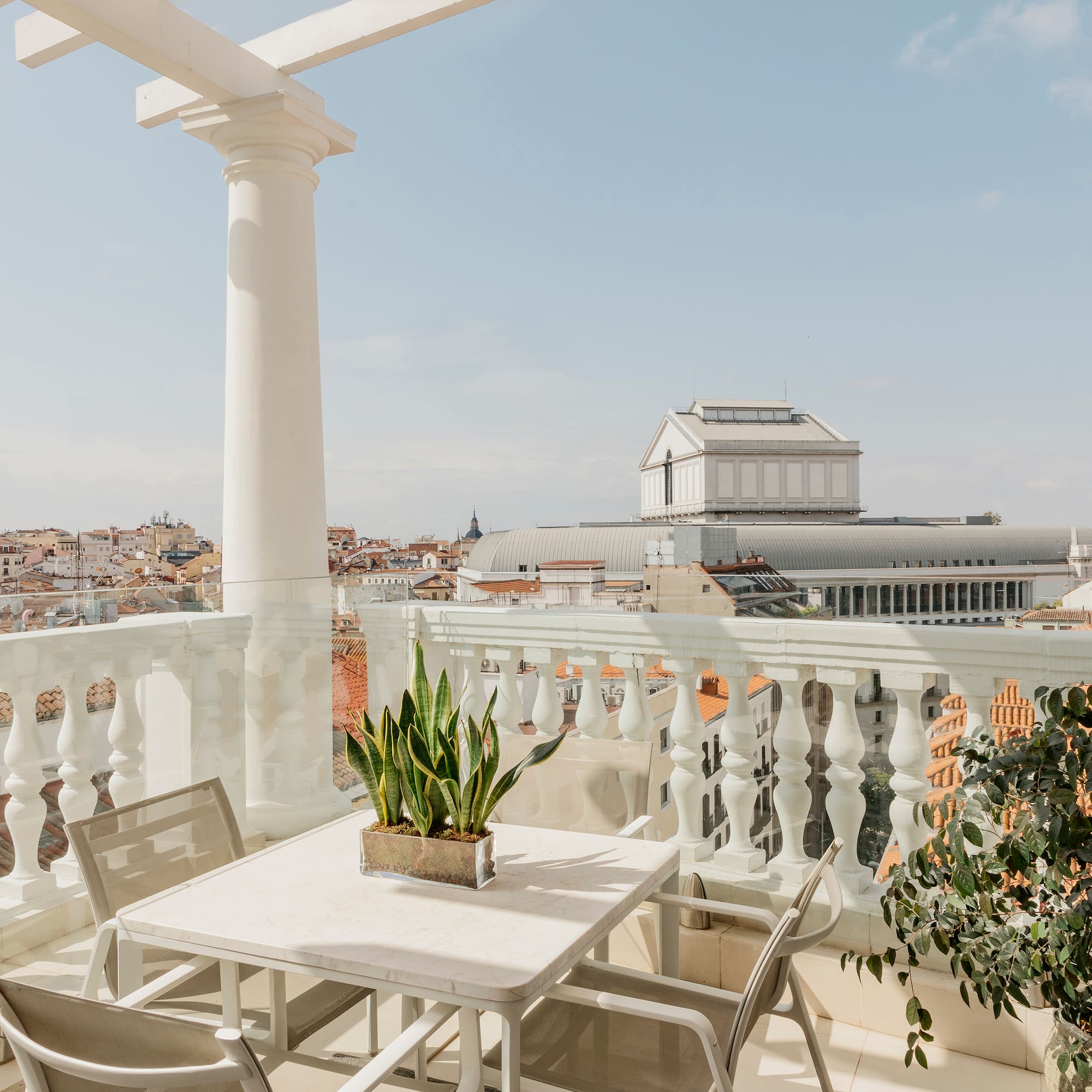 a table and chairs on a balcony with a city in the background