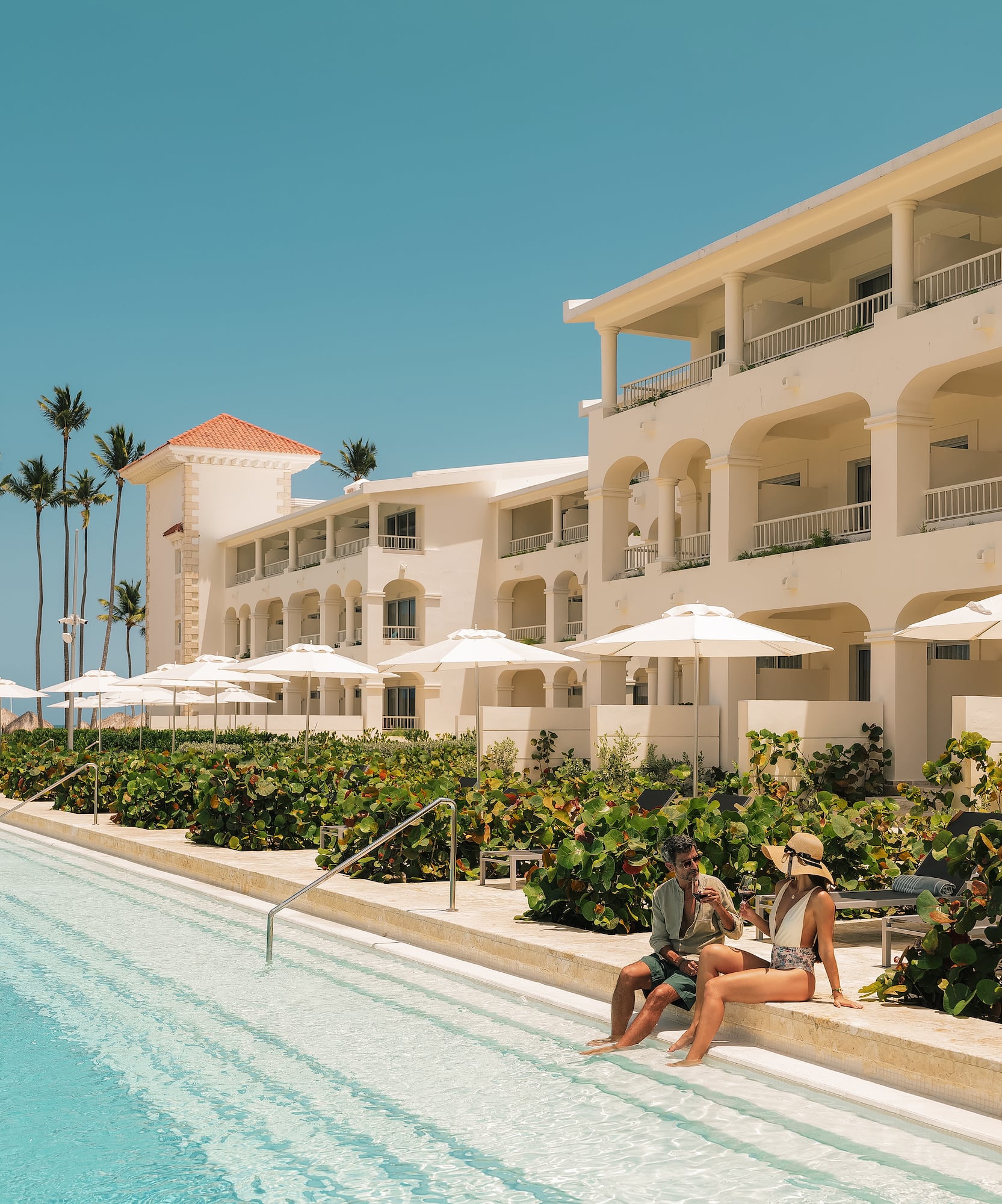 a man and woman sitting on a pool side