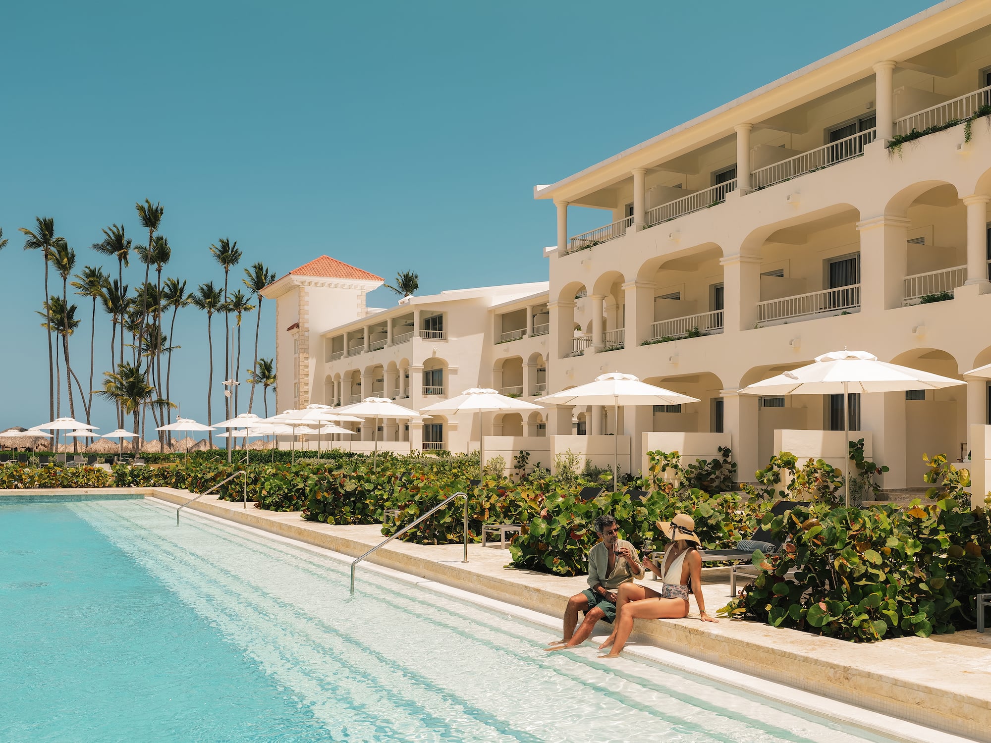 a man and woman sitting on a pool side