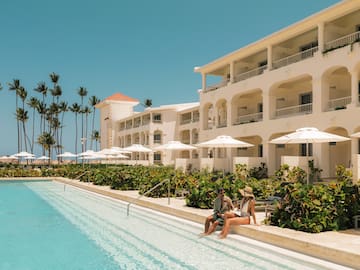 a man and woman sitting on a pool side