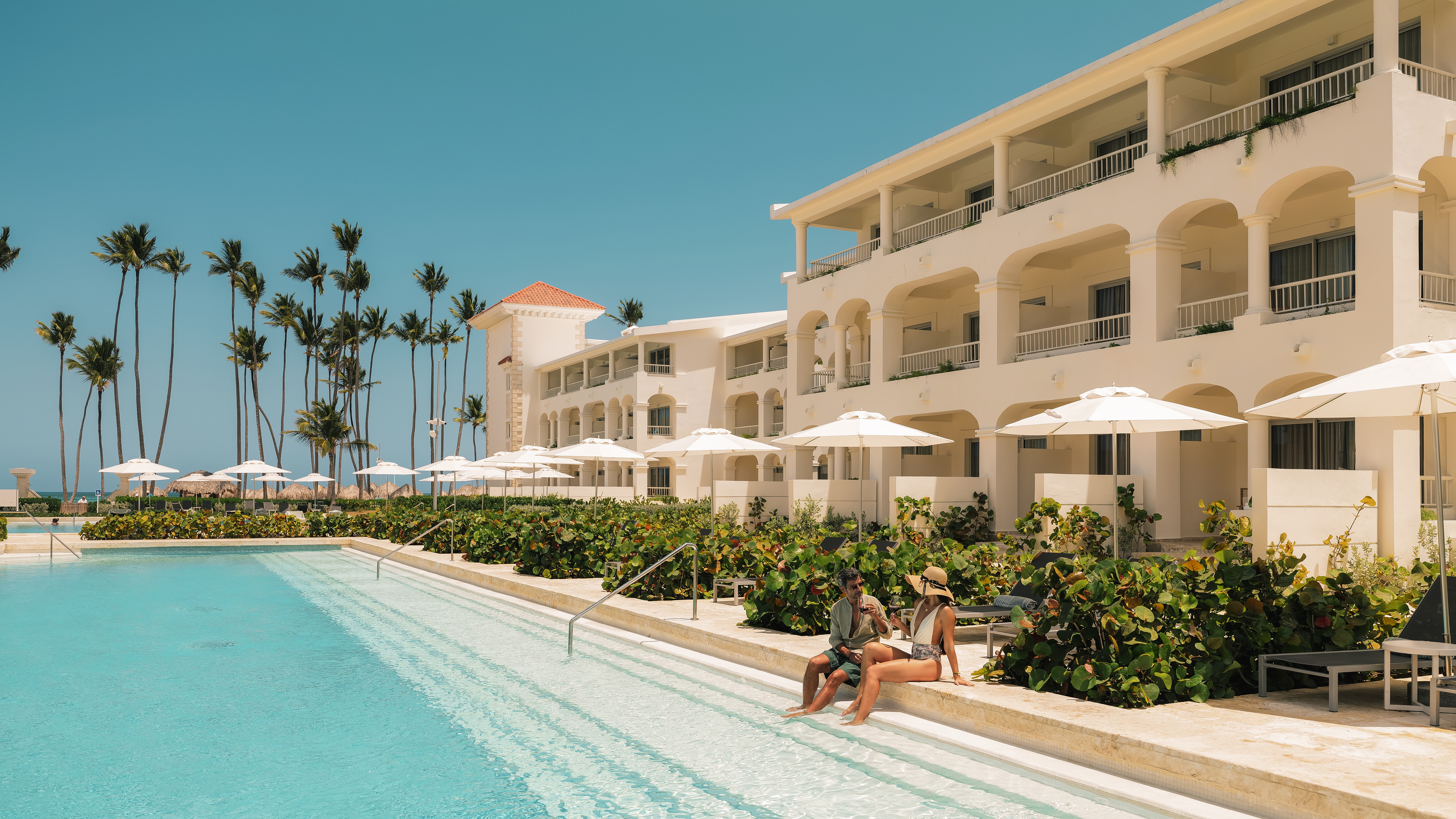 a man and woman sitting on a pool side