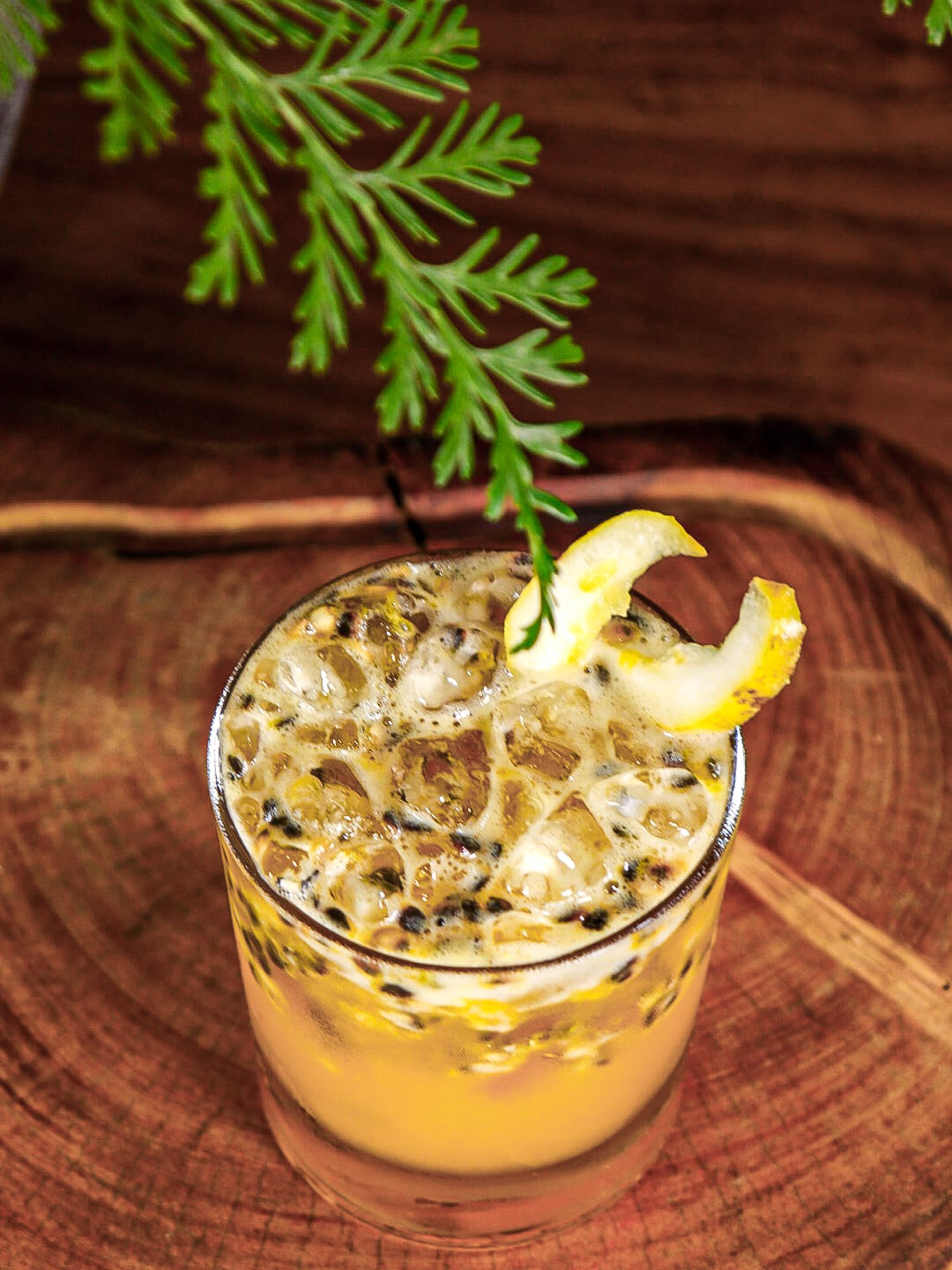 a glass of liquid with a lemon wedge and a branch