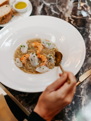 a person holding a spoon in a bowl of food