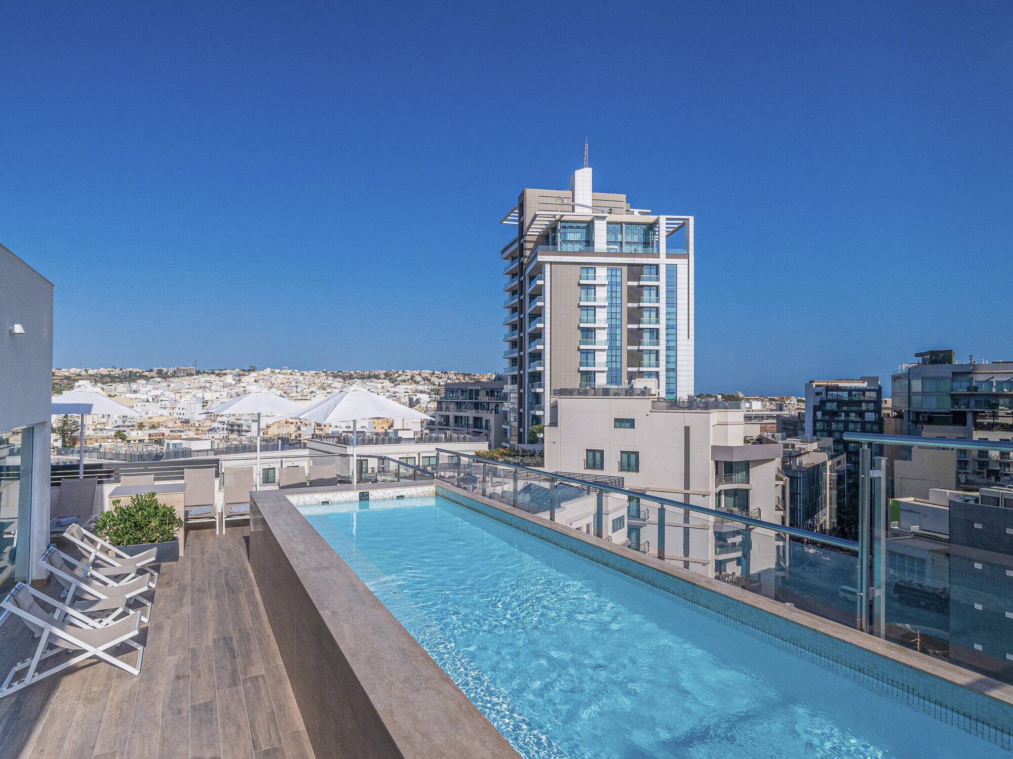 a pool with a deck and chairs on a rooftop
