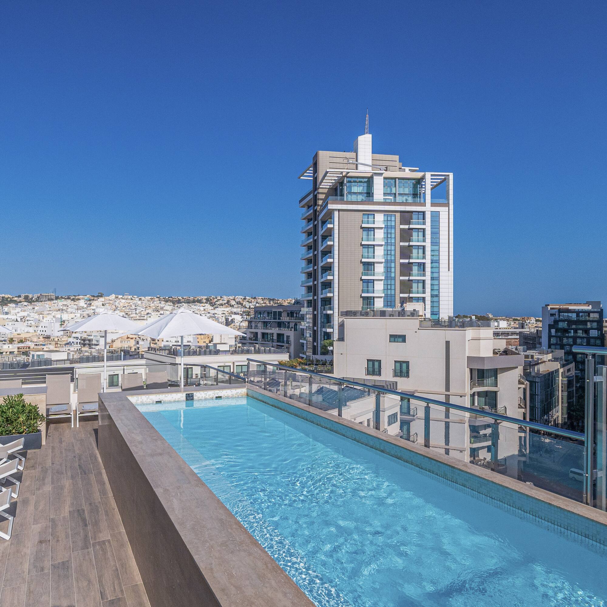a pool with a deck and chairs on a rooftop