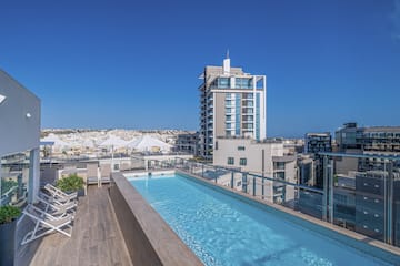 a pool with a deck and chairs on a rooftop