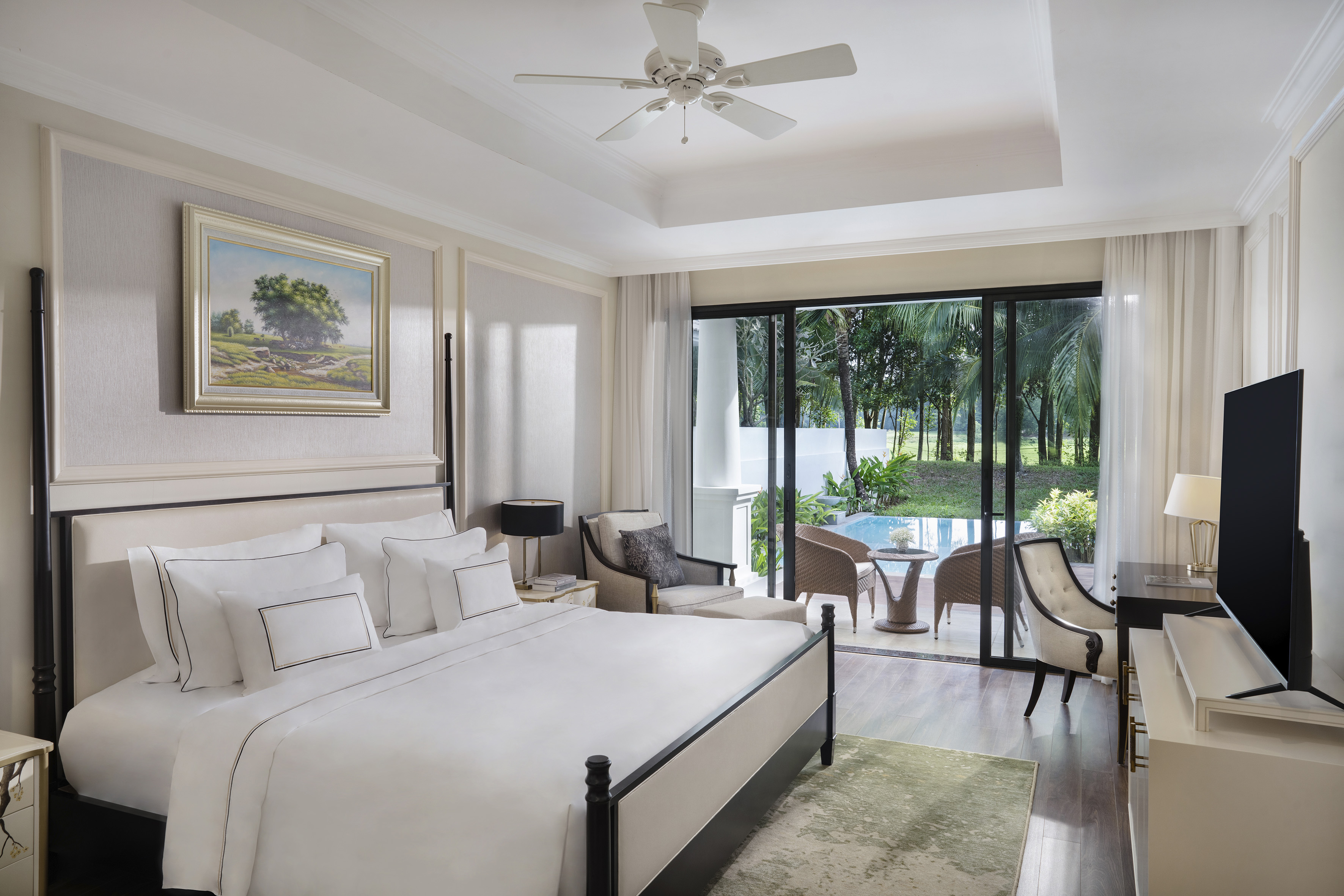 Luxury bedroom with king bed, private patio, and tropical pool view.