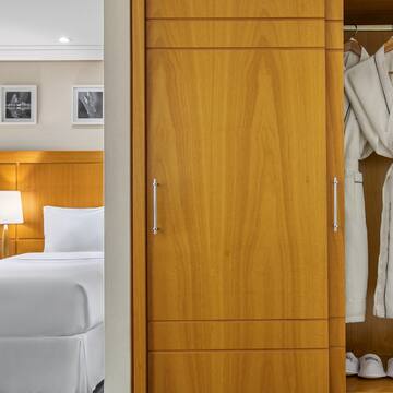 a closet with white bathrobes and a bed