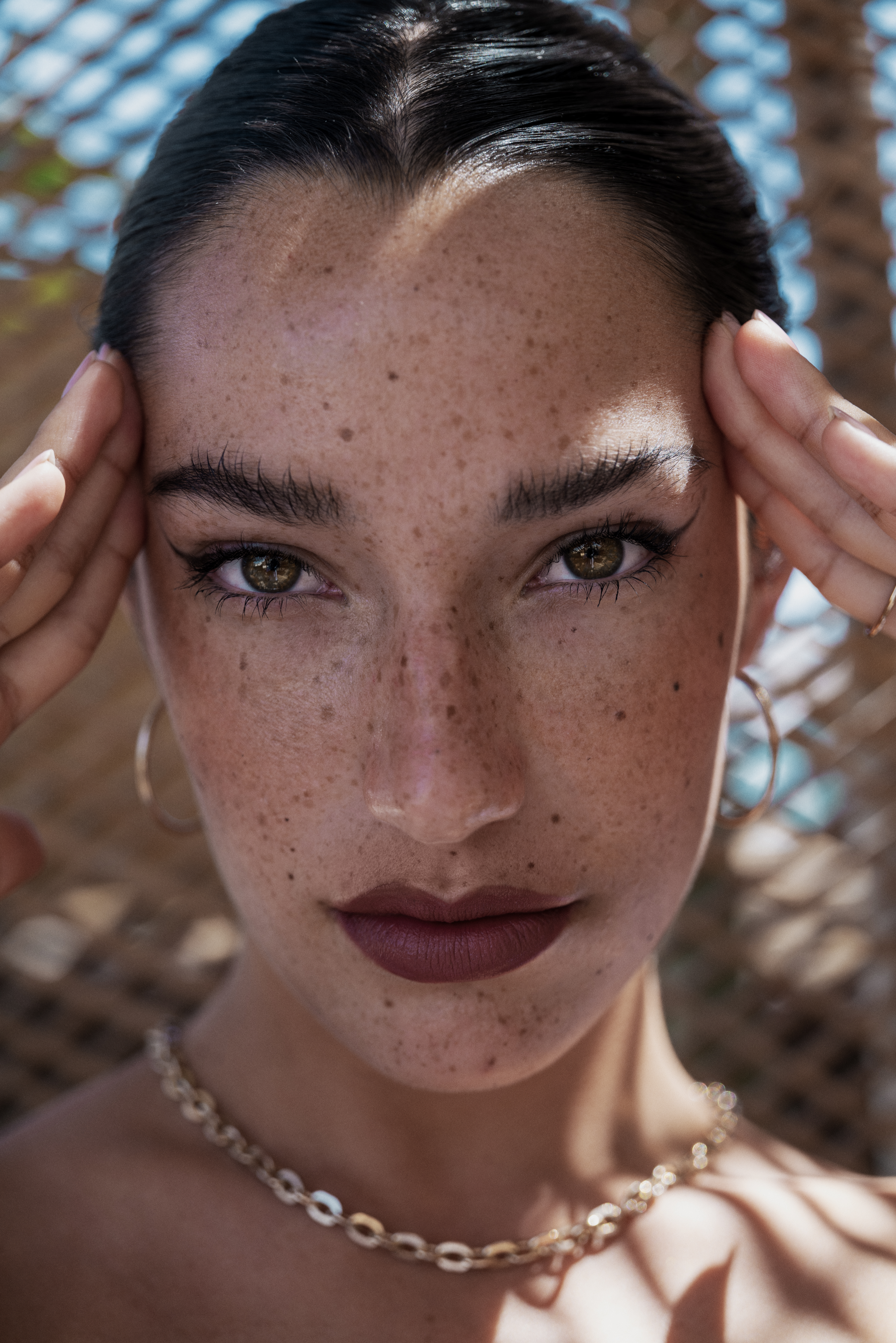 a woman with freckles holding her head