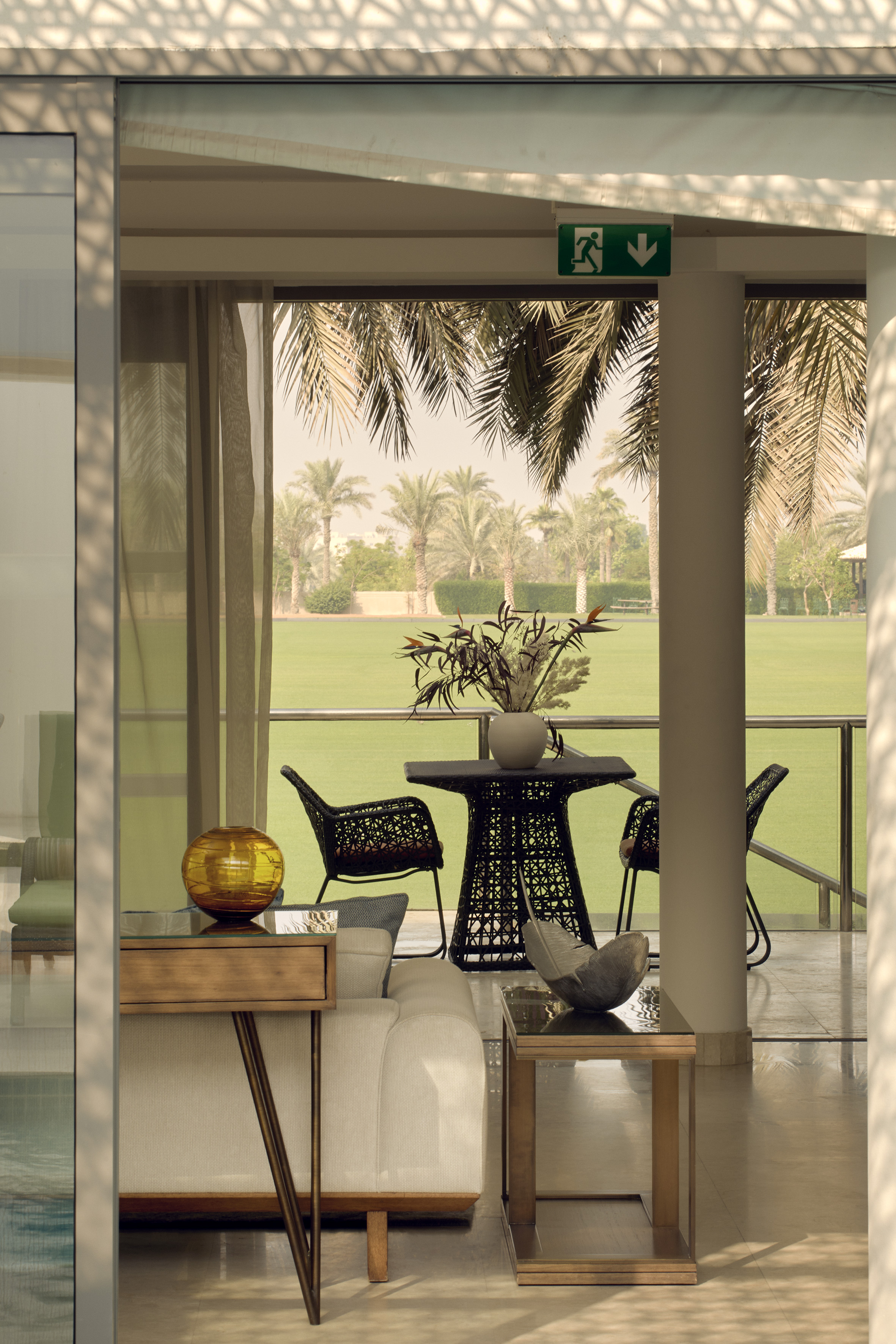 Contemporary patio with rattan furniture, sofa, green lawn, and palm trees.
