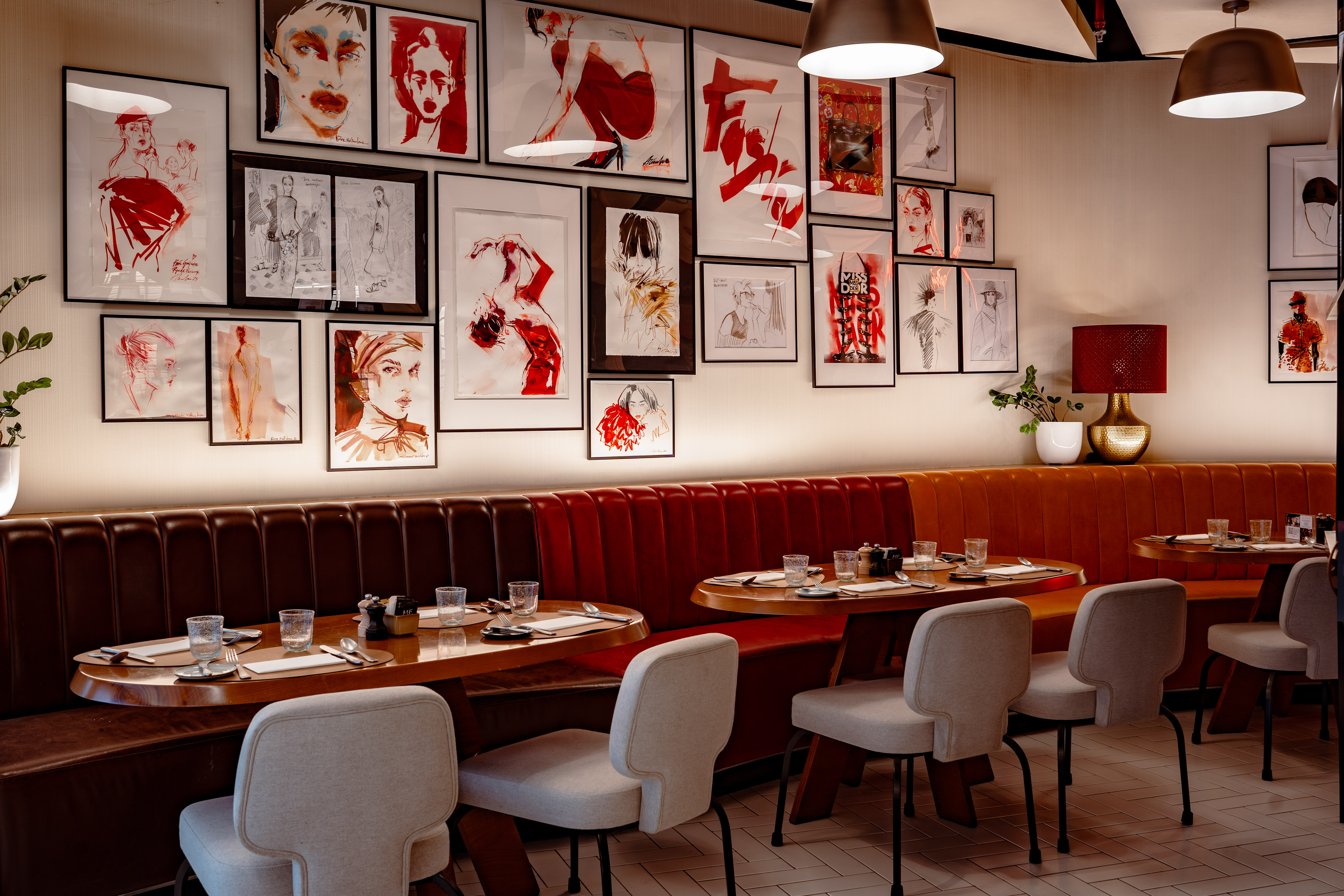 Restaurant dining area with brown leather booths and fashion art gallery wall.