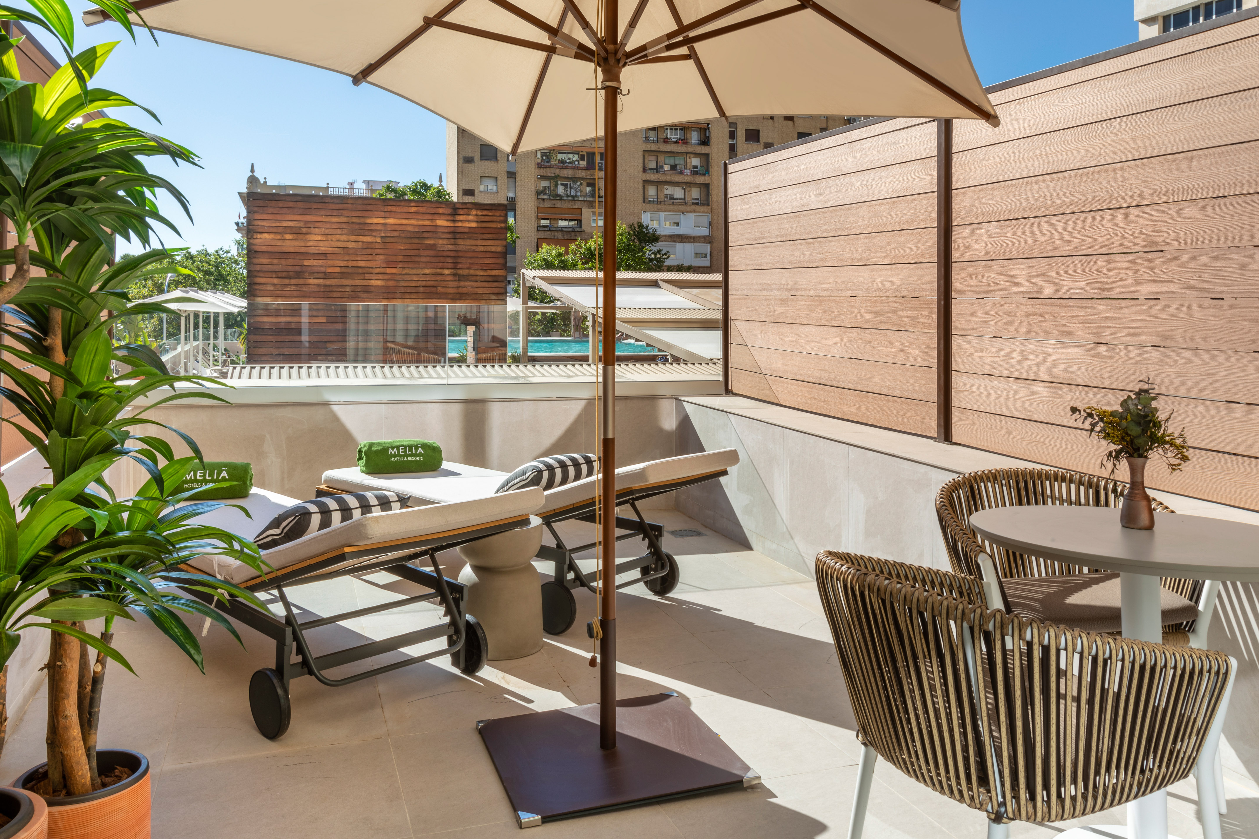 Meliá hotel terrace with sun loungers, umbrella, and outdoor seating.