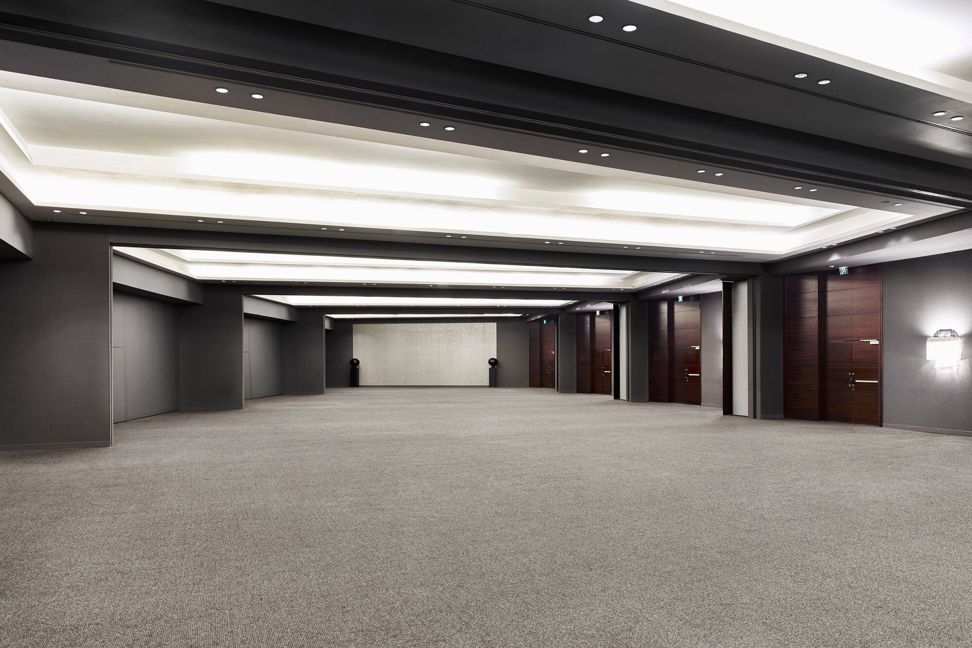 Empty modern ballroom with brown carpet and contemporary lighting.