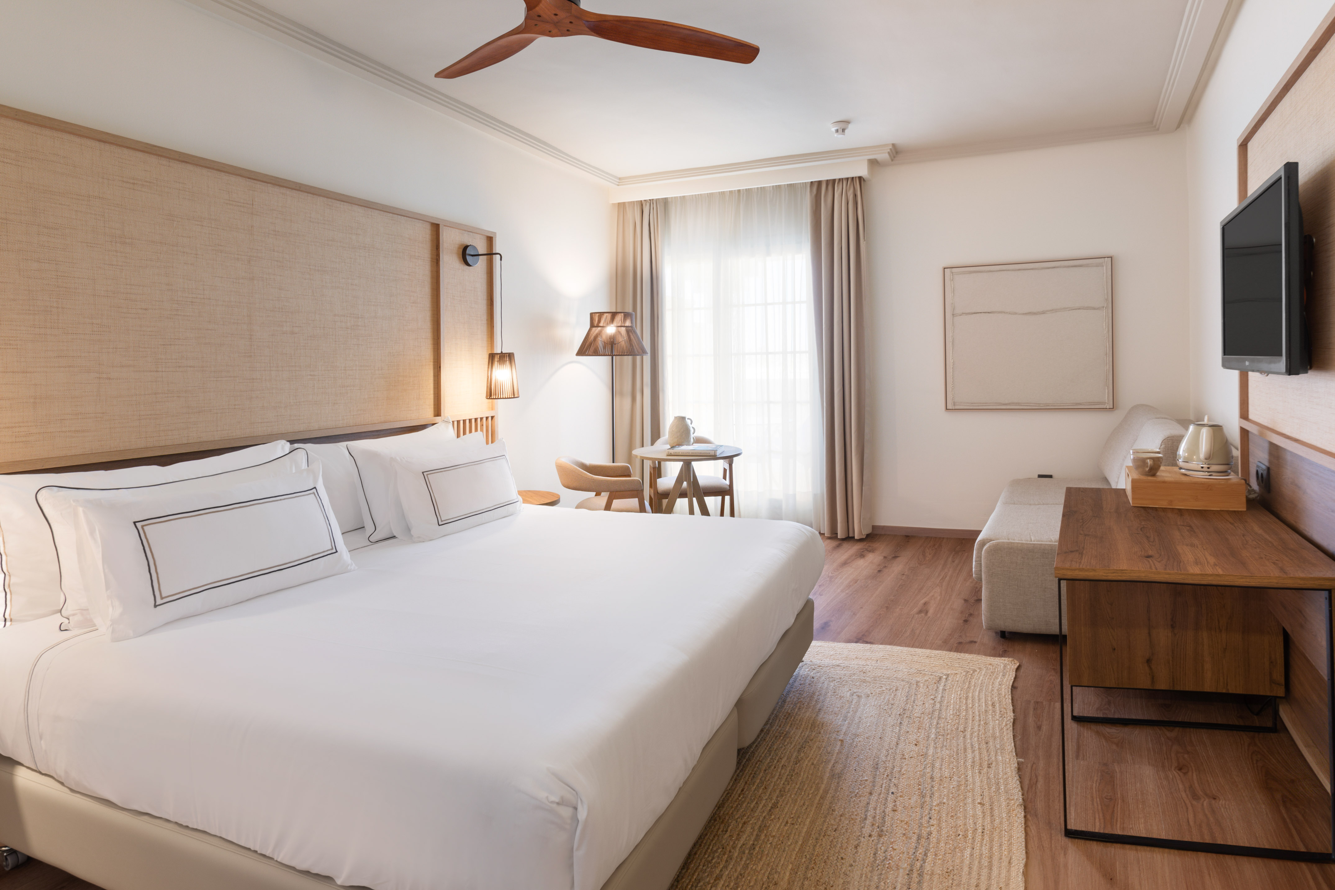 a room with a bed and a table and a fan