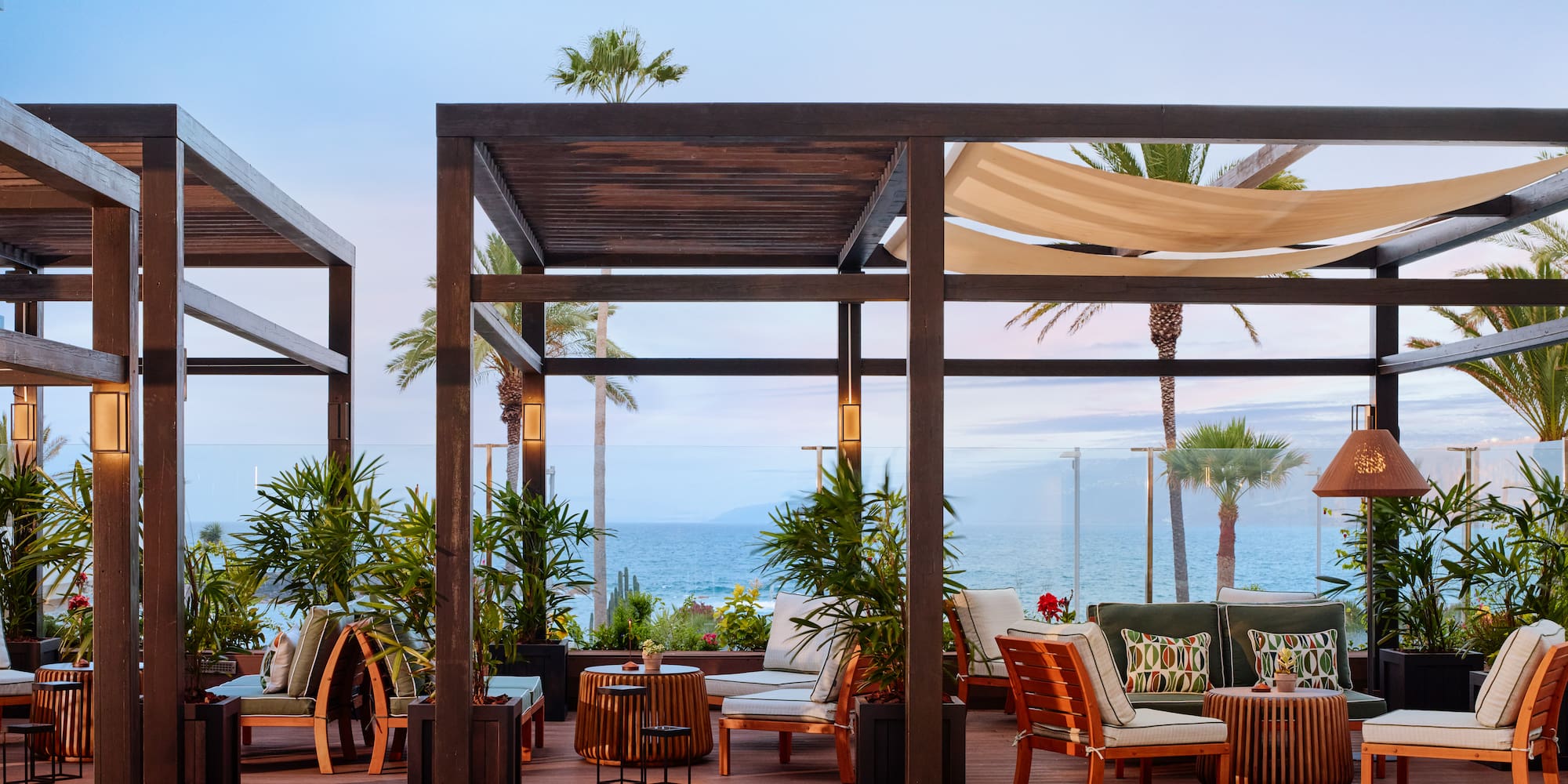 a patio with chairs and tables on a deck overlooking the ocean