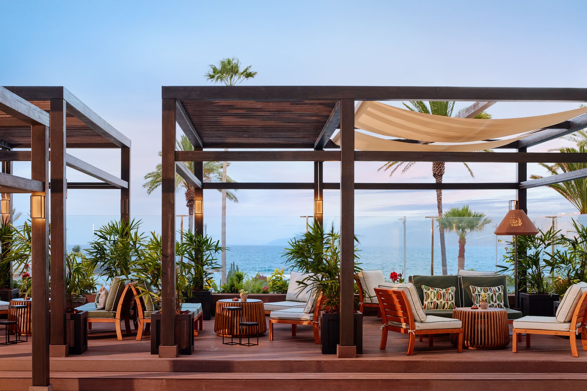 a patio with chairs and tables on a deck overlooking the ocean