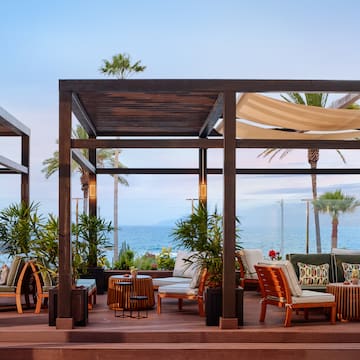 a patio with chairs and tables on a deck overlooking the ocean
