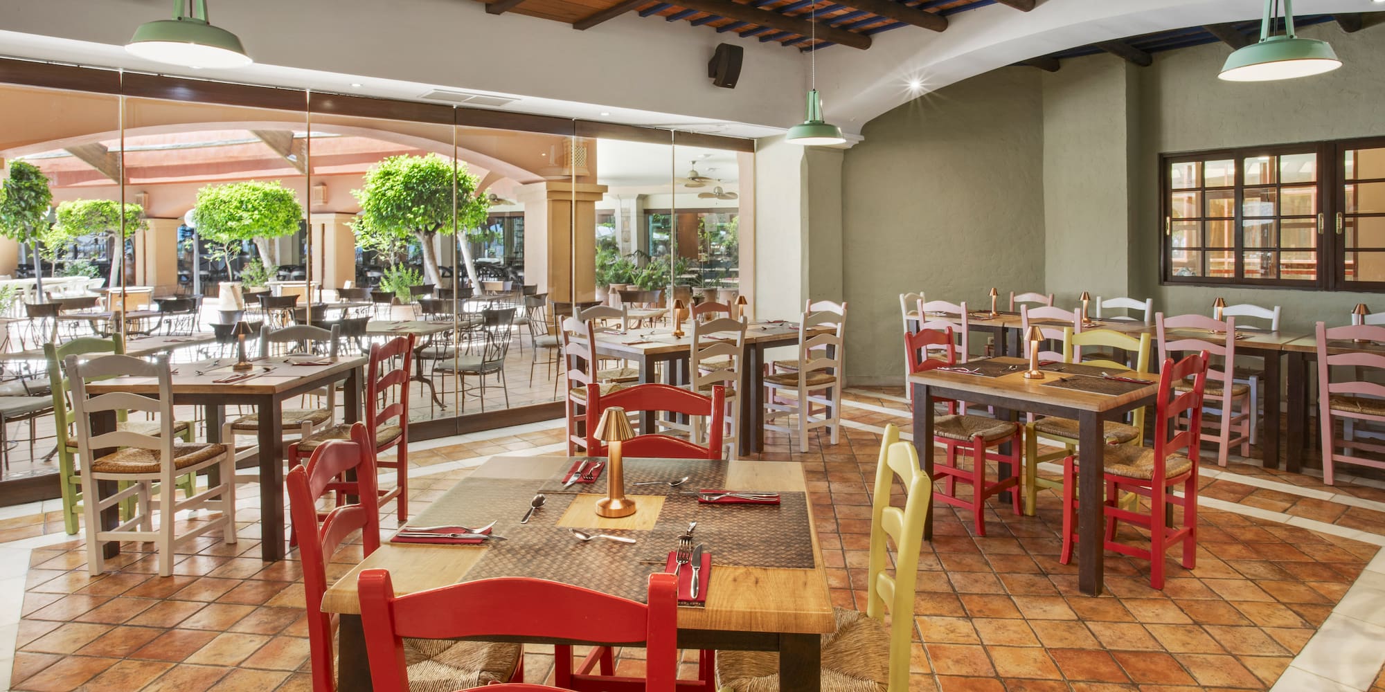 Mediterranean restaurant interior with colorful seating, terracotta tiles, and patio view.