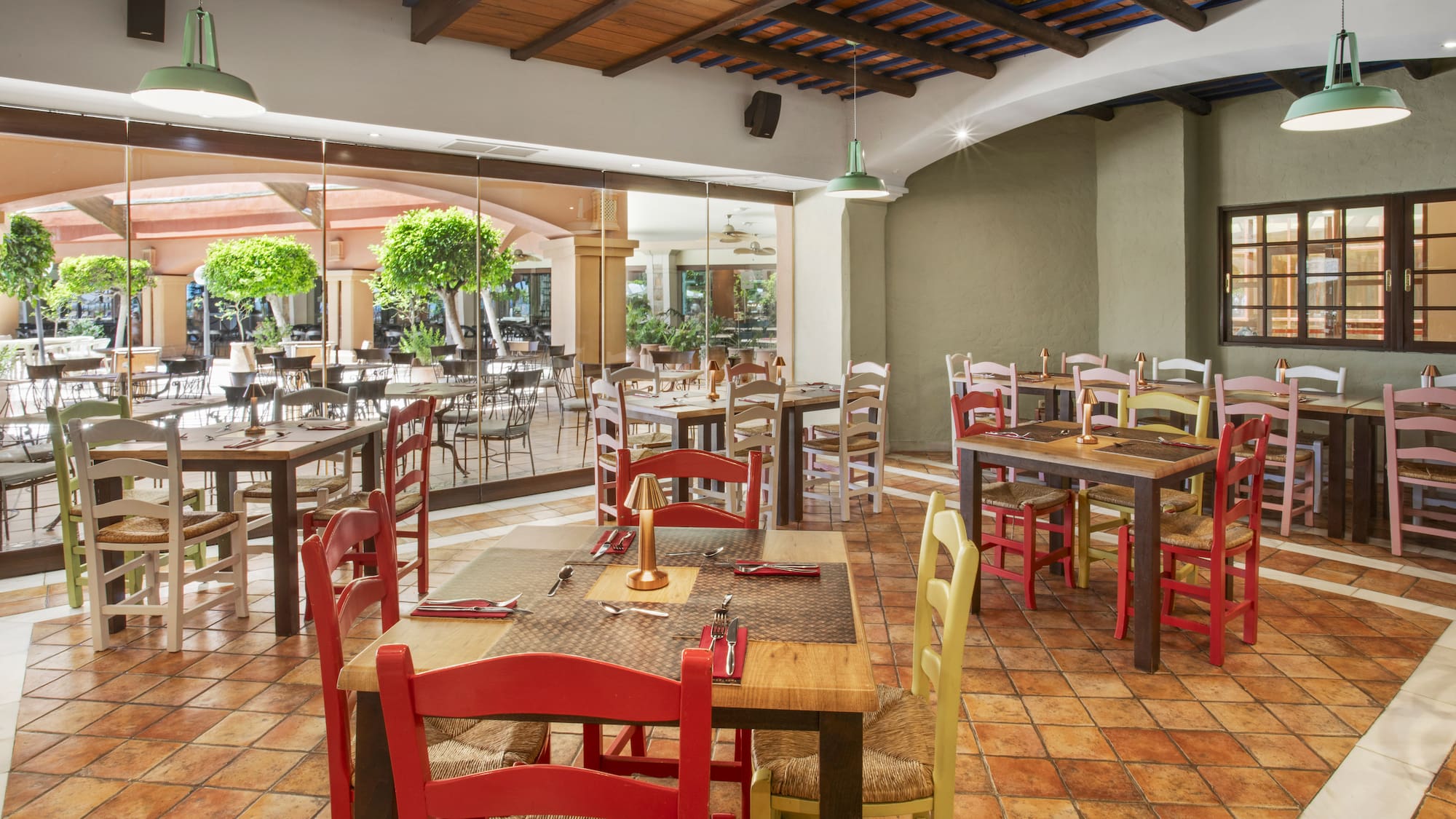 Mediterranean restaurant interior with colorful seating, terracotta tiles, and patio view.