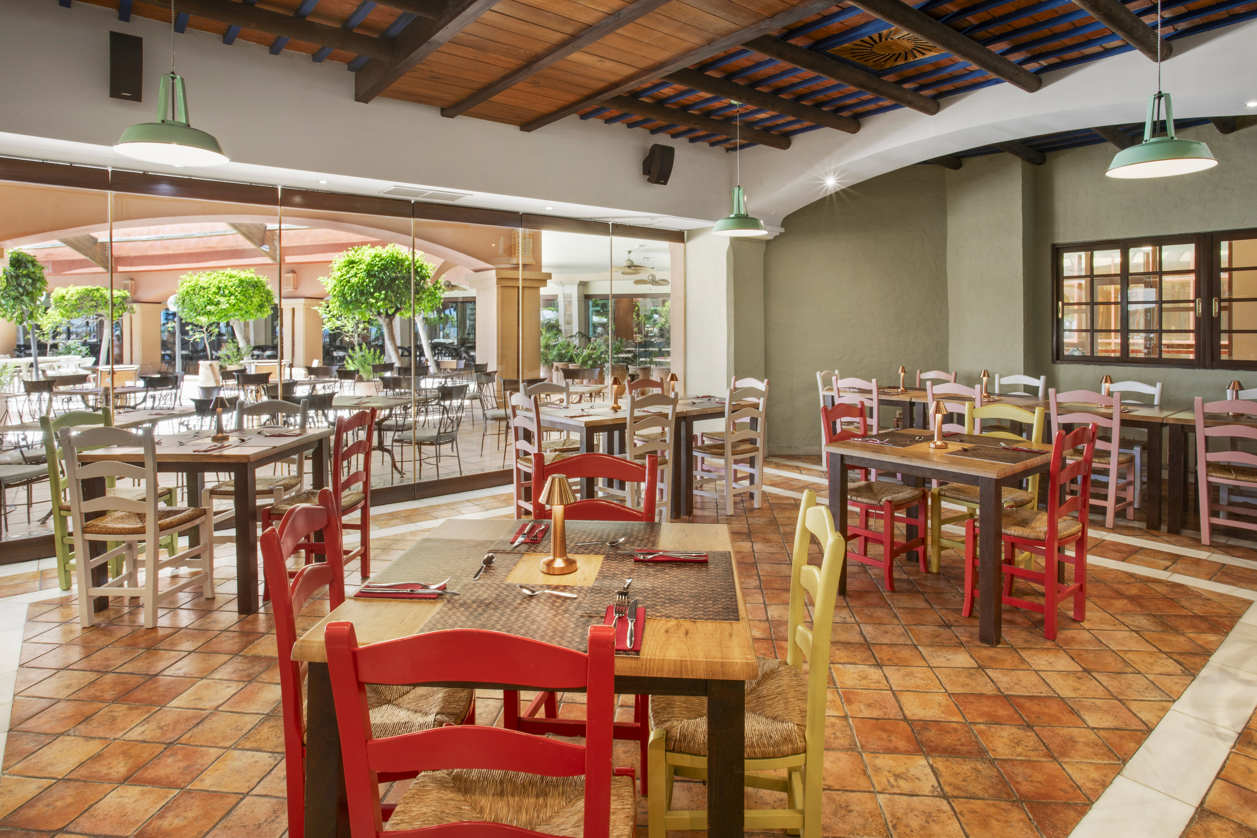 Mediterranean restaurant interior with colorful seating, terracotta tiles, and patio view.