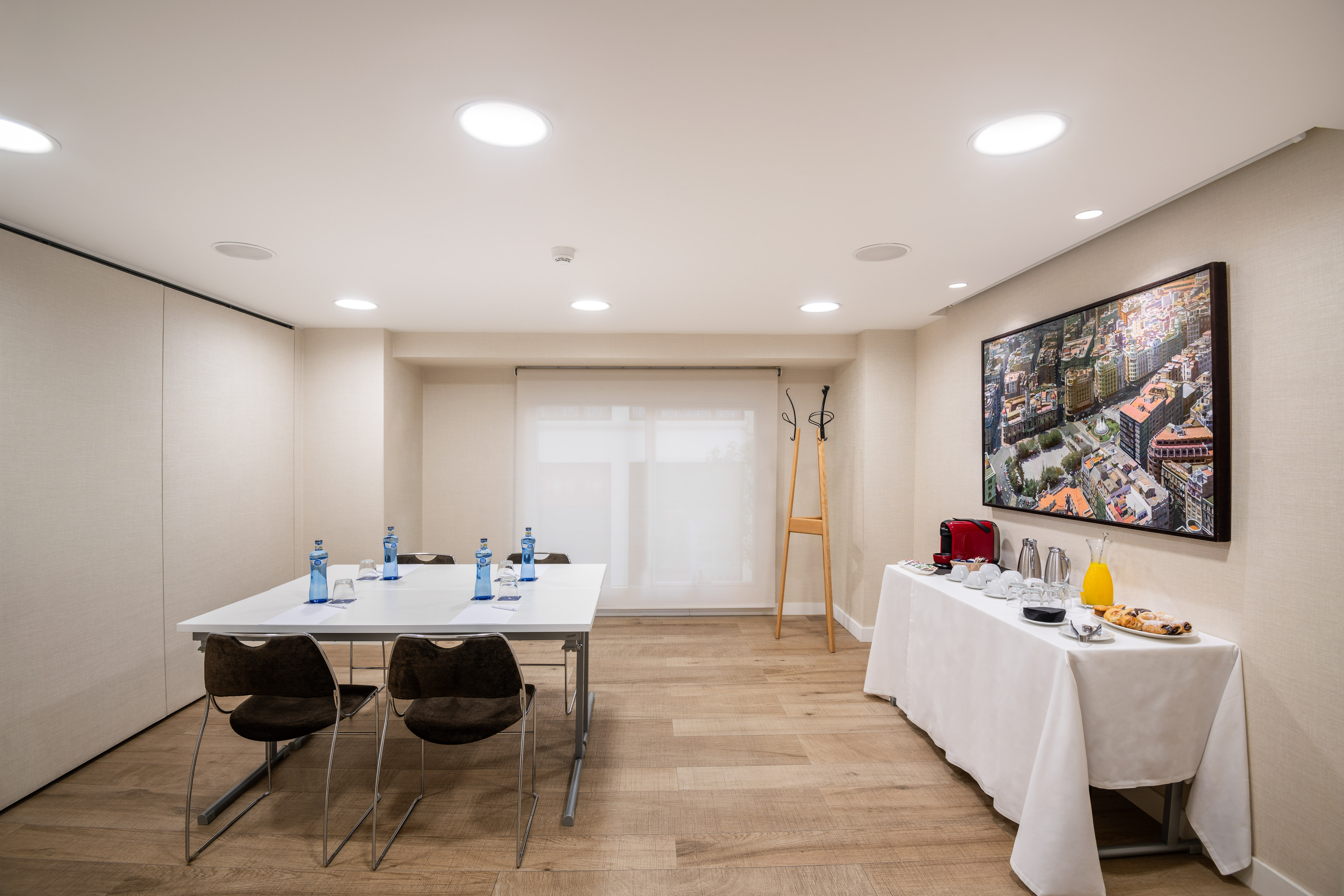 Hotel meeting room with conference table, chairs, and refreshment buffet.