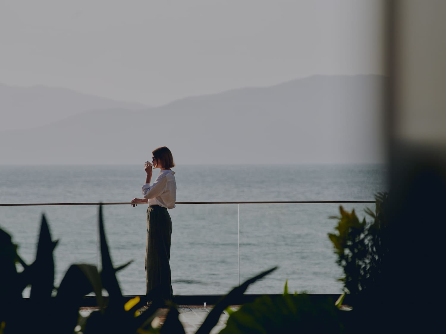 a woman standing on a balcony overlooking the ocean
