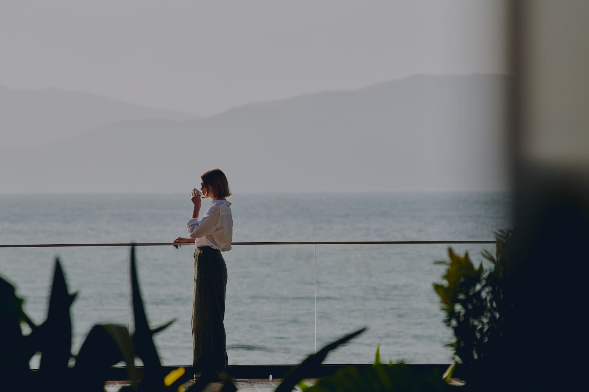 a woman standing on a balcony overlooking the ocean