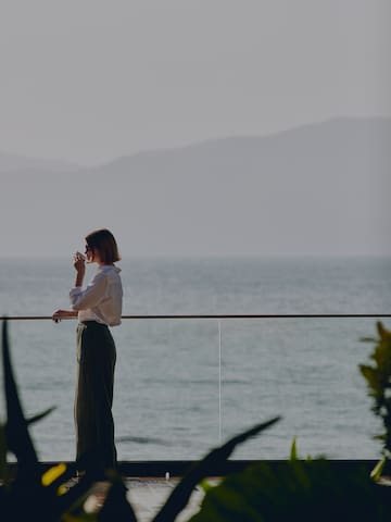 a woman standing on a balcony overlooking the ocean