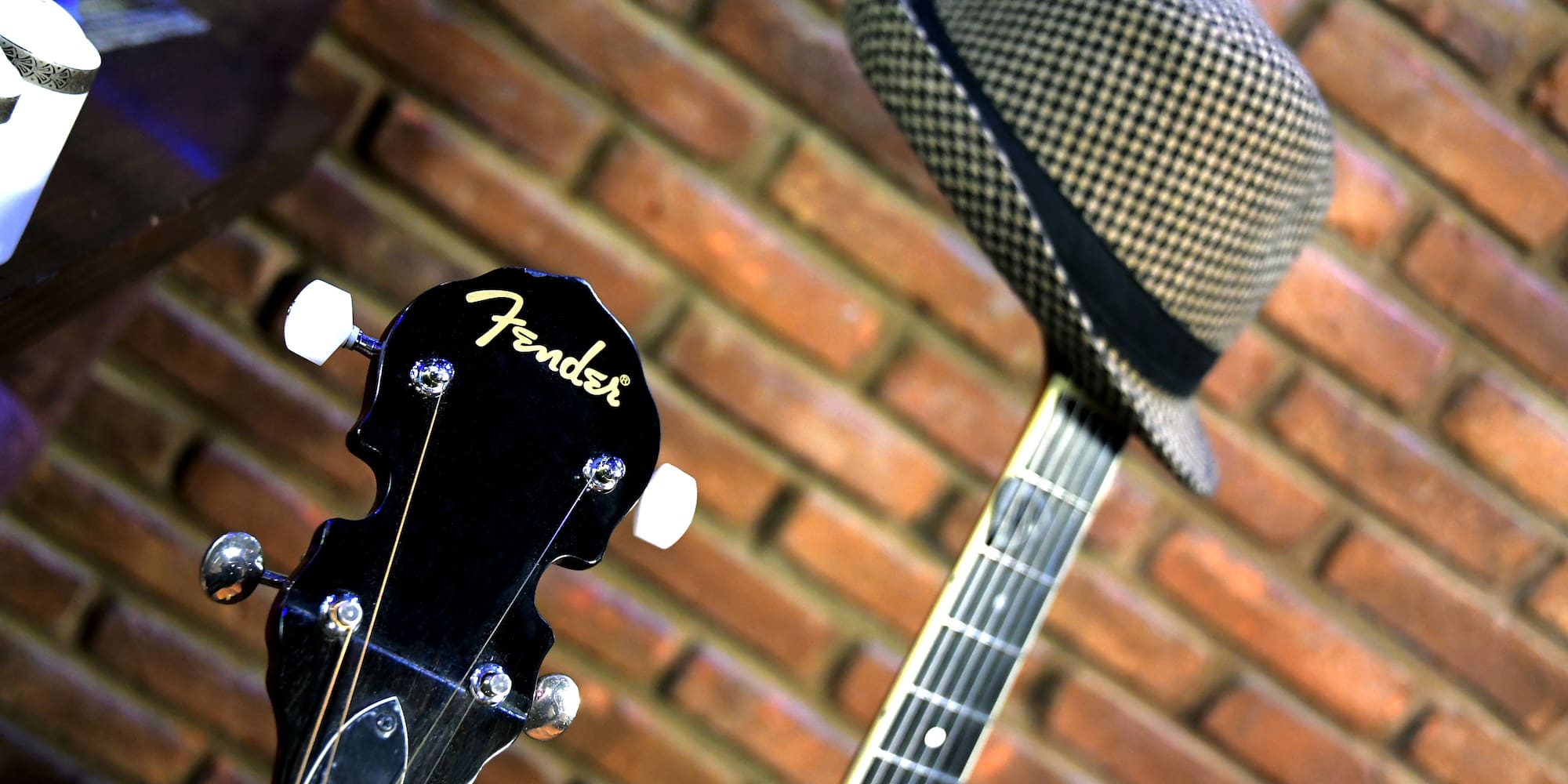 a guitar and hat on a brick wall