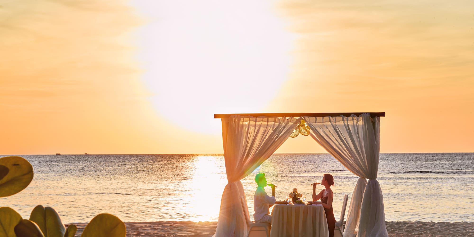 a couple sitting at a table on a beach