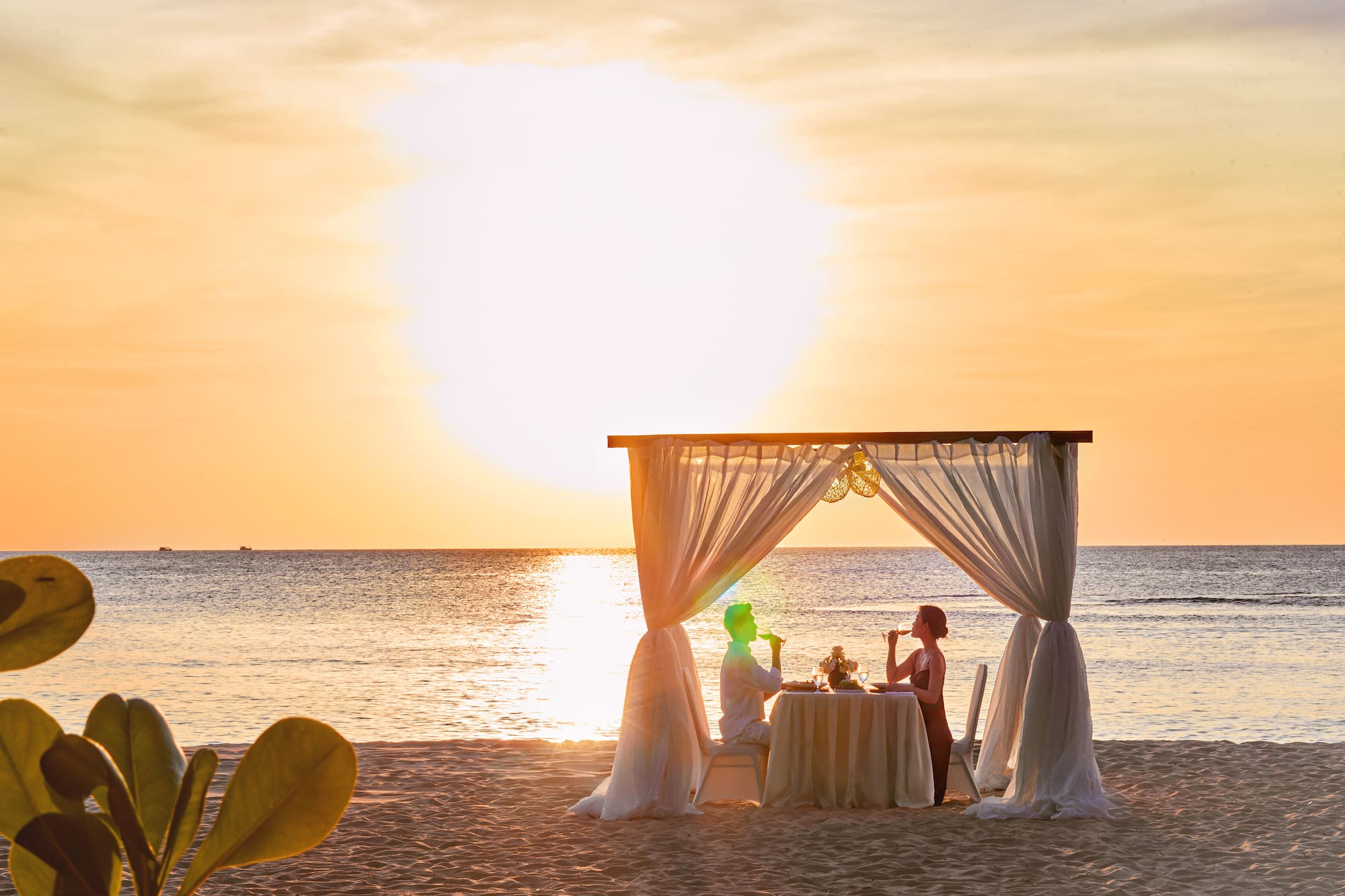 a couple sitting at a table on a beach