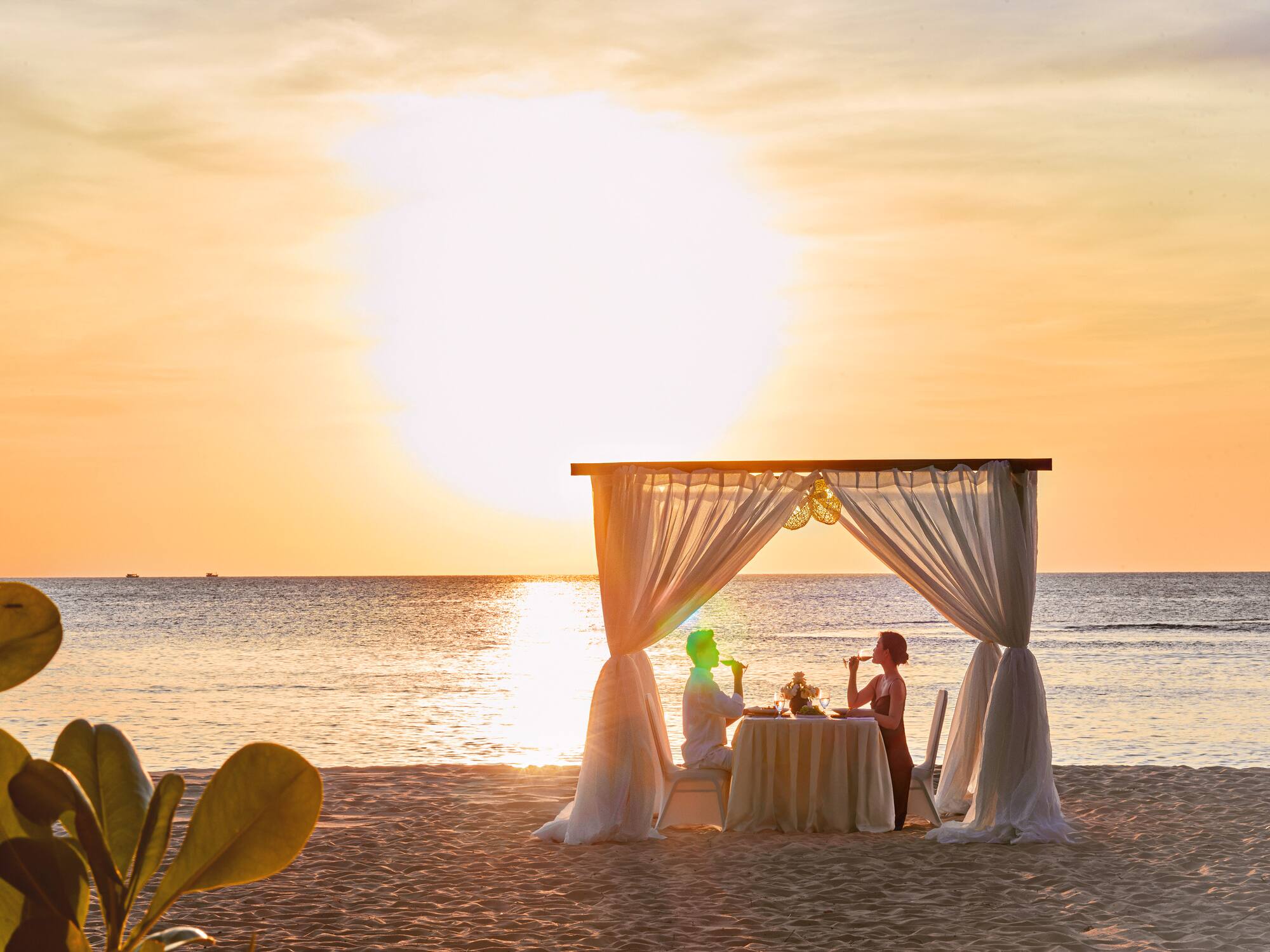 a couple sitting at a table on a beach