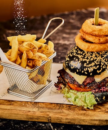 a burger and fries on a wooden board