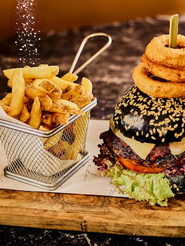 a burger and fries on a wooden board