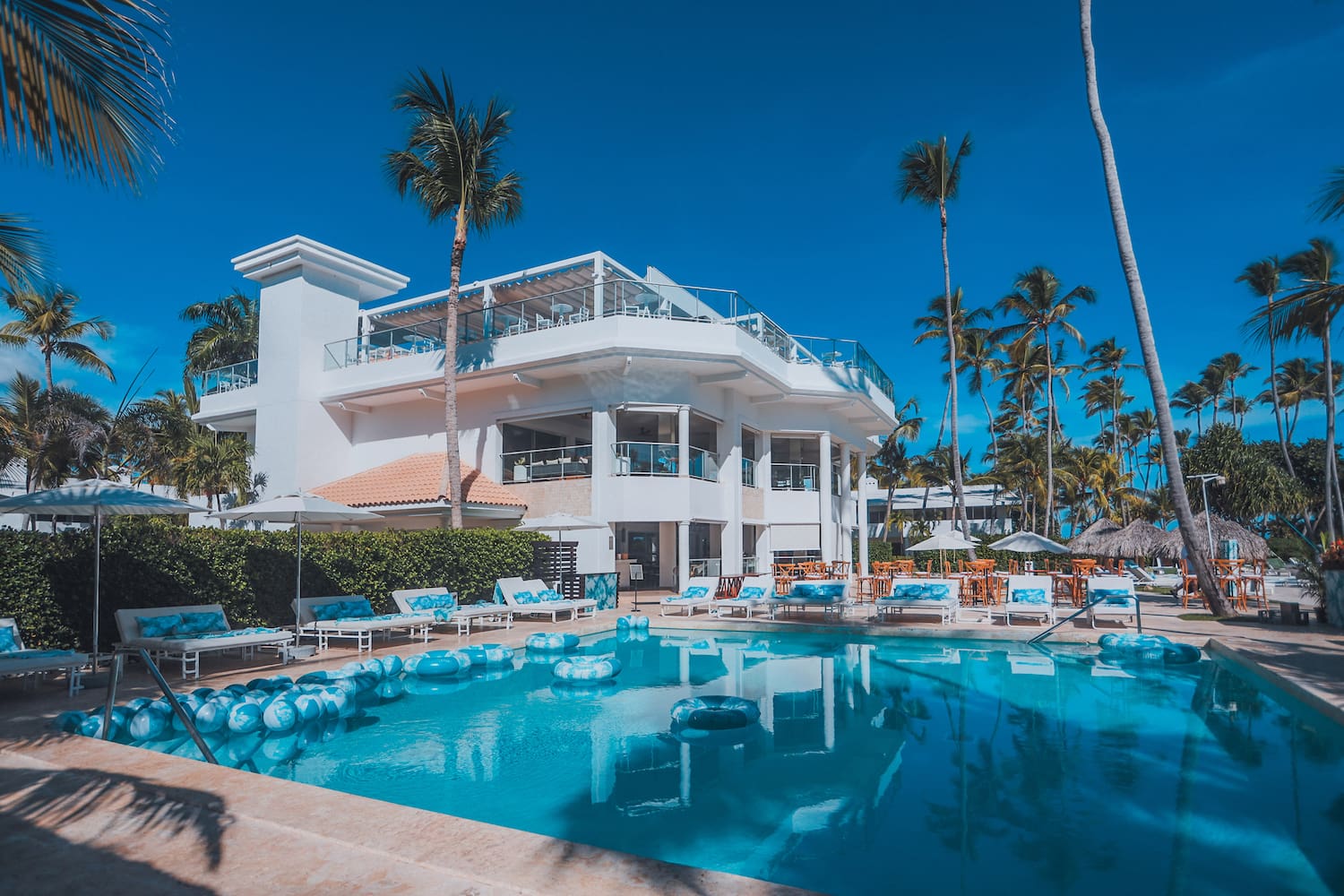 a pool with lounge chairs and a building with palm trees