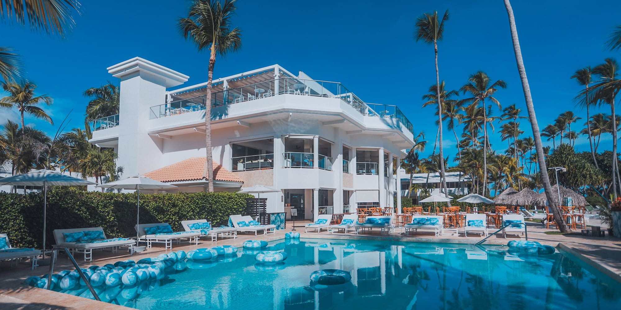 a pool with lounge chairs and a building with palm trees