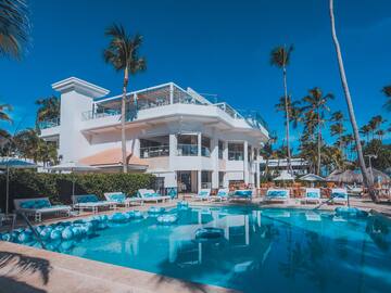 a pool with lounge chairs and a building with palm trees