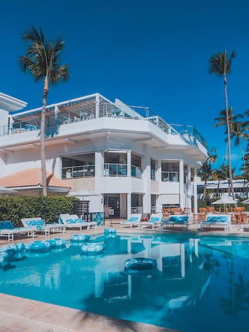 a pool with lounge chairs and a building with palm trees