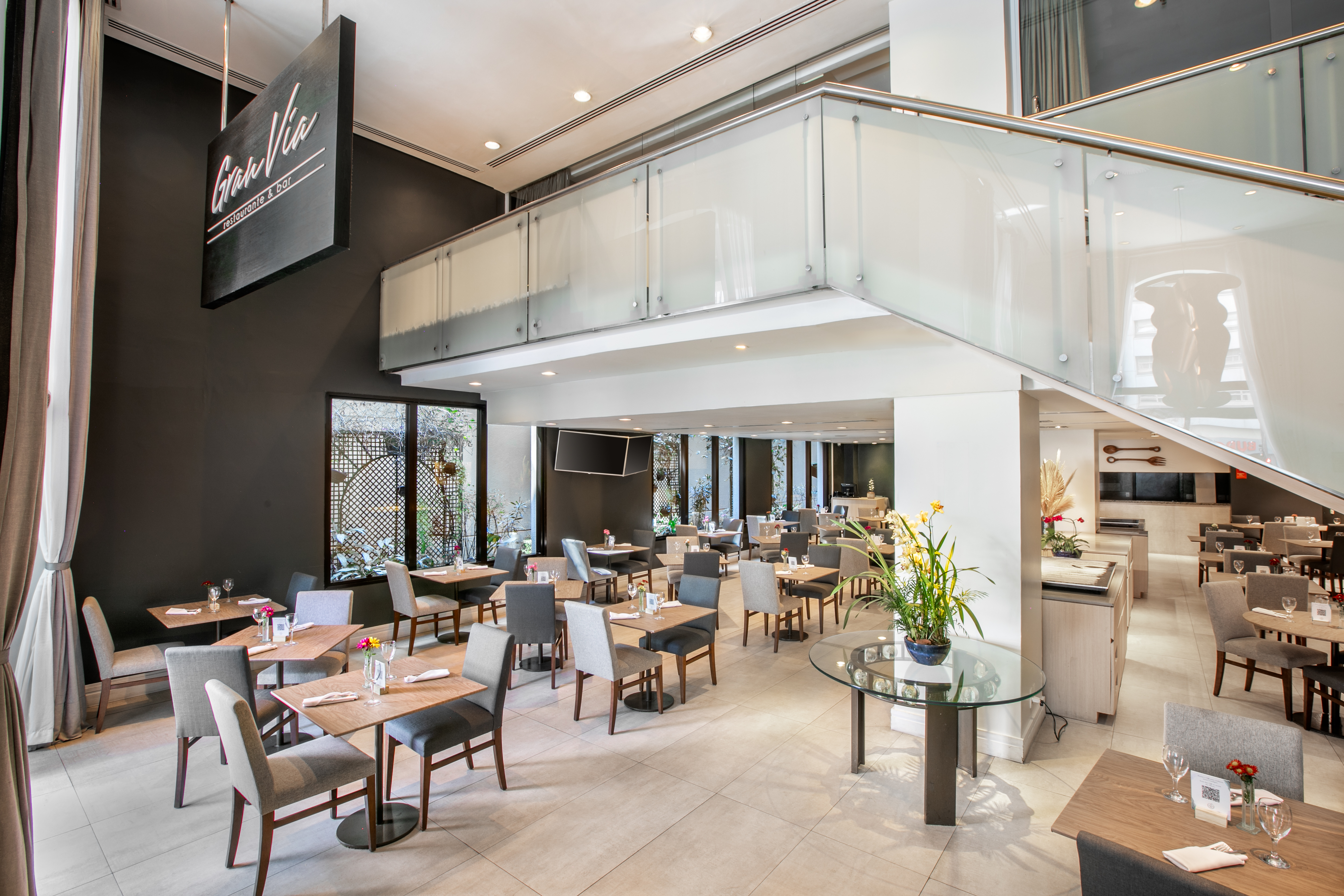 Gran Via restaurant interior: modern tables, chairs, and glass staircase.