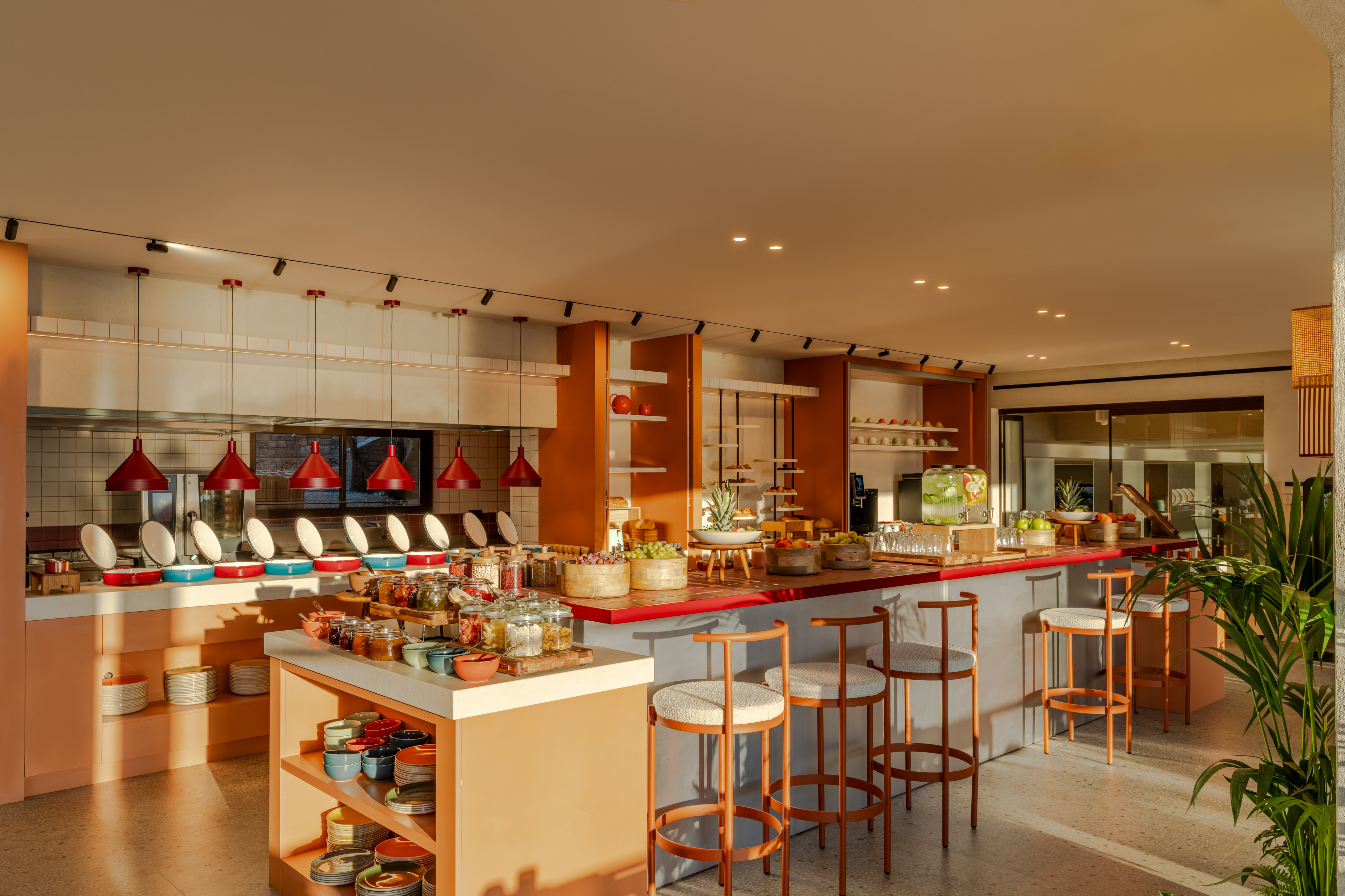 Hotel breakfast buffet with fresh fruit, hot food, and modern bar seating.
