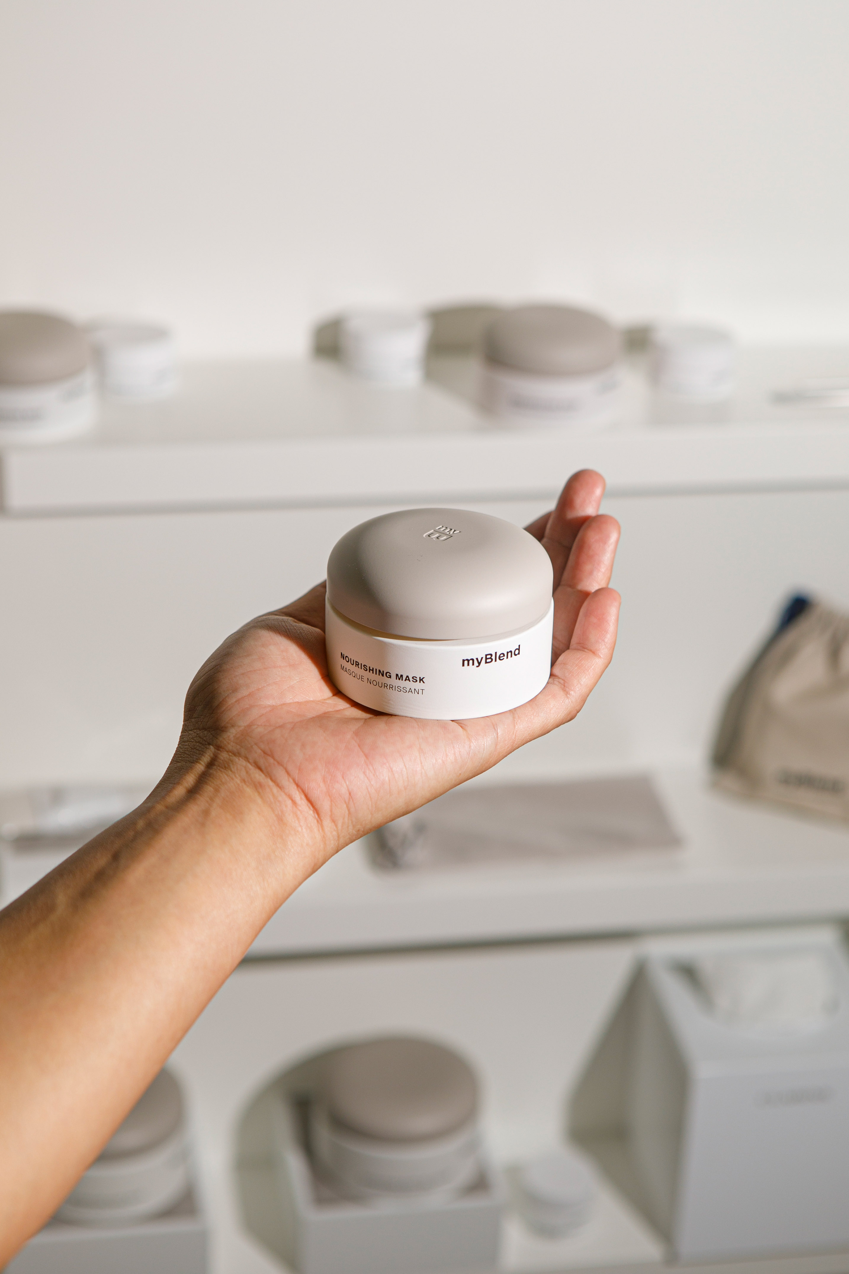 Hand holding myBlend Nourishing Mask jar. White and beige skincare cream.