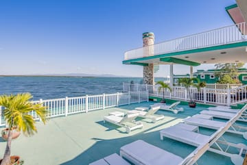 a deck with chairs and a white railing overlooking the water