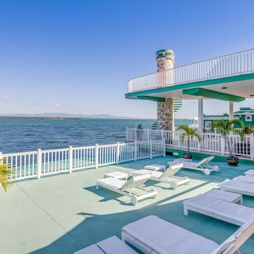 a deck with chairs and a white railing overlooking the water