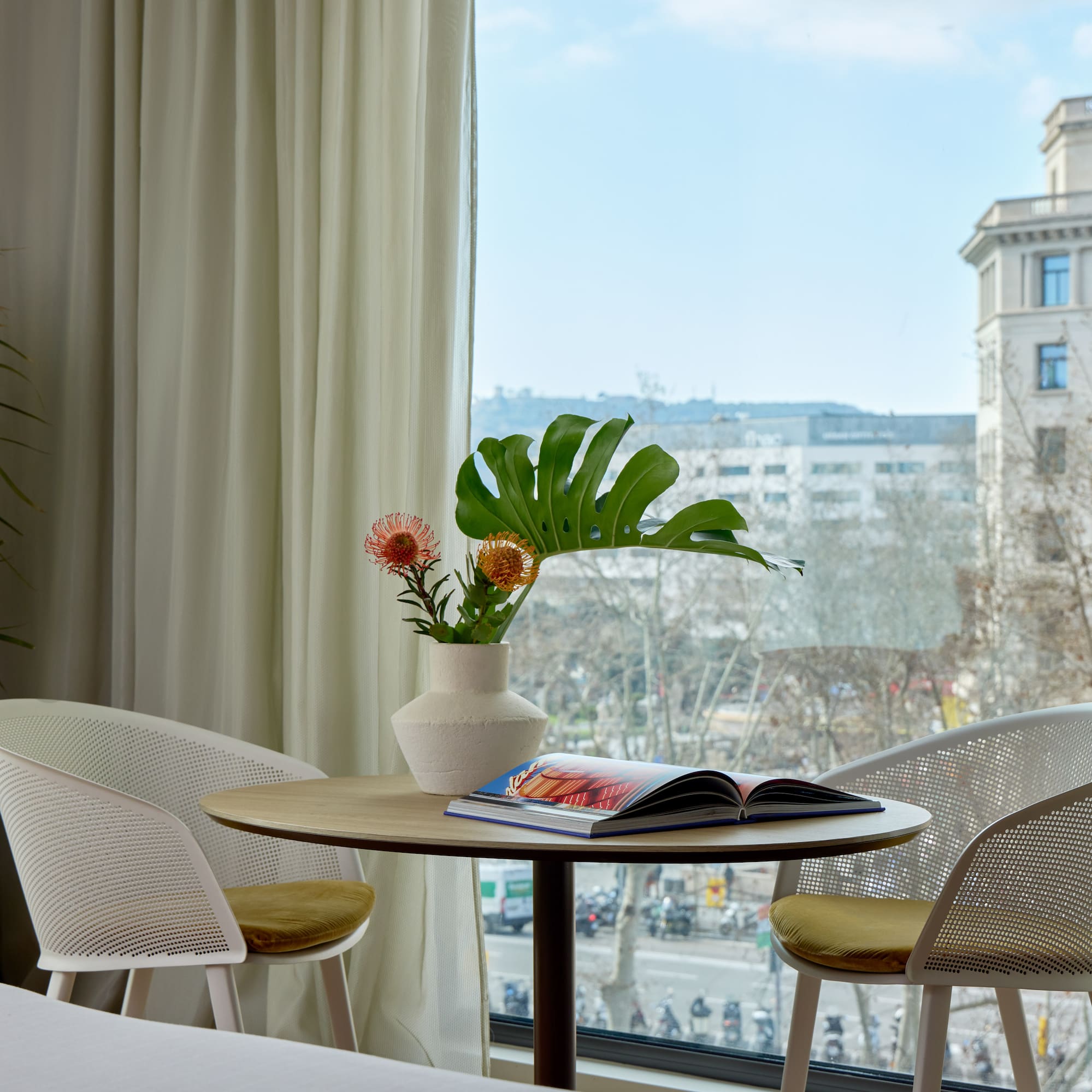 a table with chairs and a vase of flowers