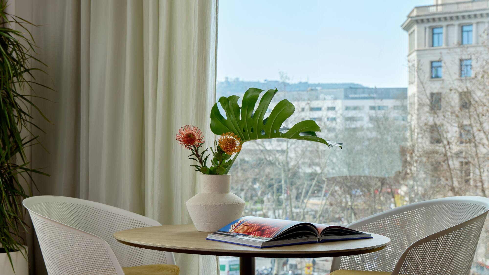 a table with chairs and a vase of flowers