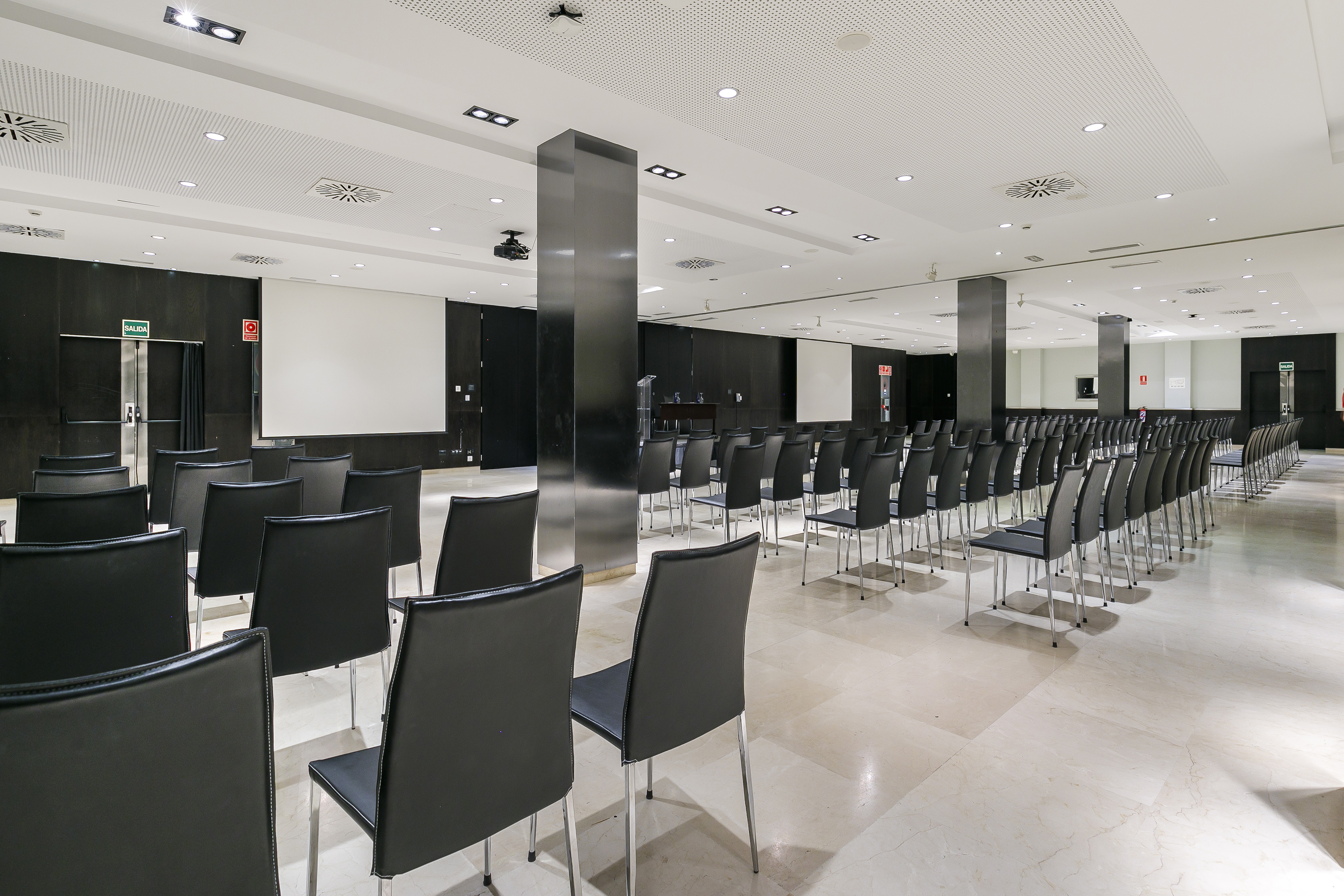 Large corporate meeting room with theater-style seating and two projector screens.