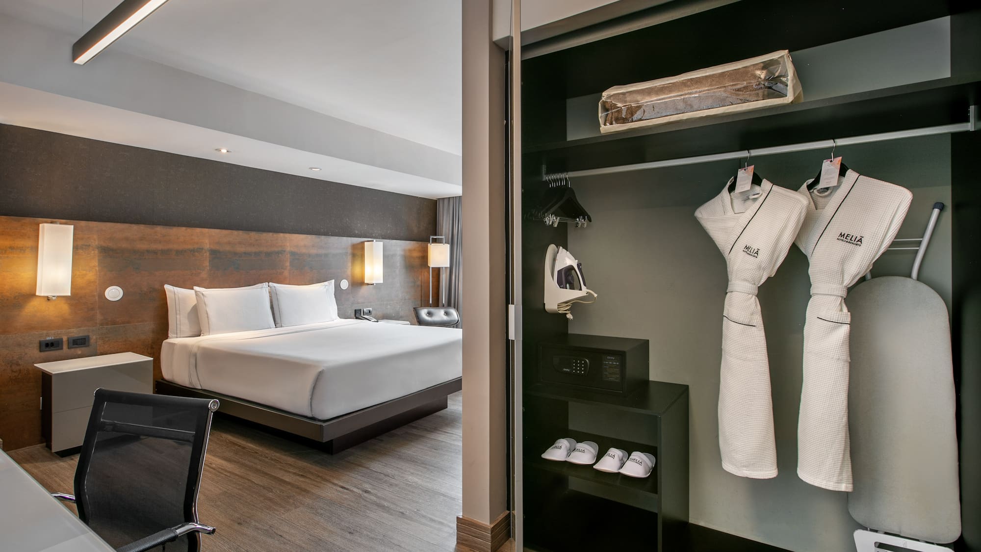 Quarto de hotel moderno com cama grande e armário aberto com roupões. - Grand Premium com Varanda - Meliá Ibirapuera, São Paulo